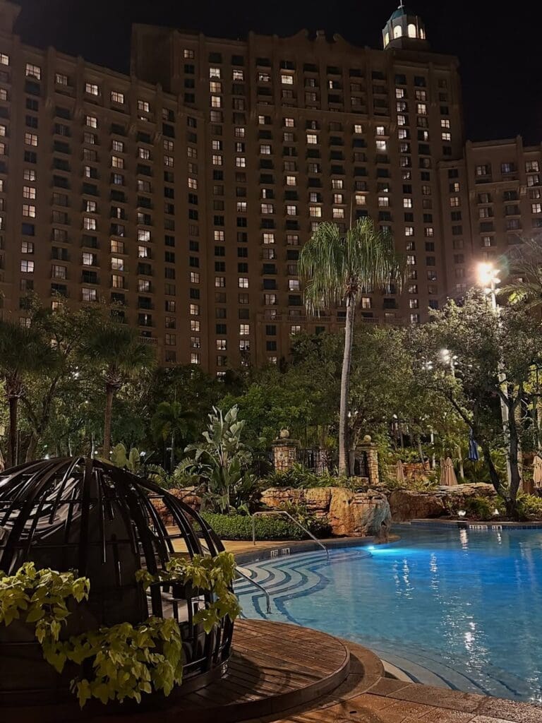 Night view of JW Marriott Orlando Grande Lakes with the pool and tropical landscaping lit up.