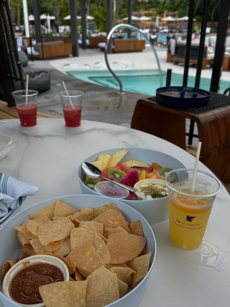 Poolside cabana snacks at JW Marriott Orlando with chips, salsa, fruit platter, and cocktails.